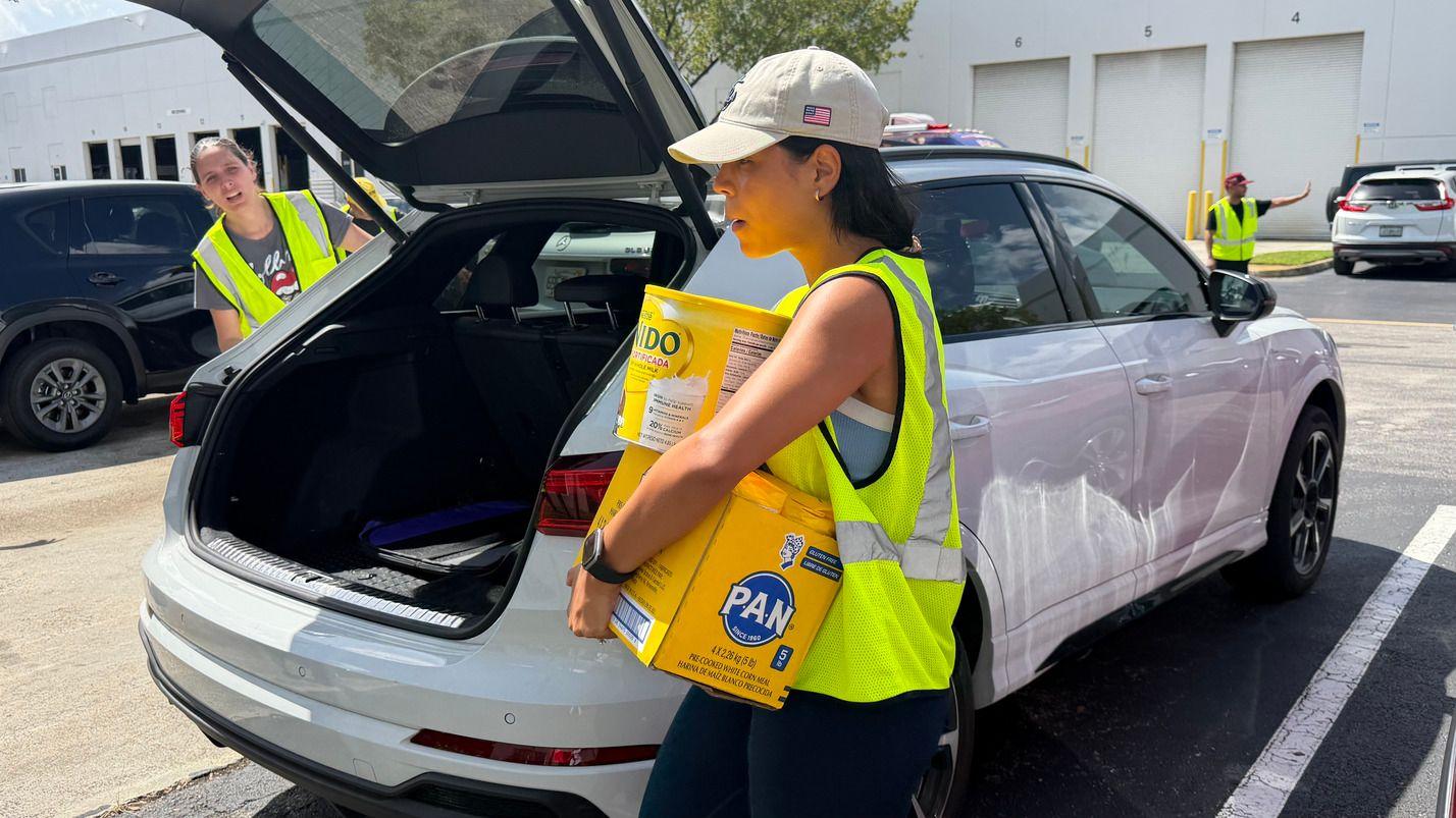 Una mujer descarga de un auto una caja de harina de maíz y una lata de leche en polvo, en el centro de donación de Global Empowerment Mission, el 25 de junio de 2025 en Doral, Florida. 