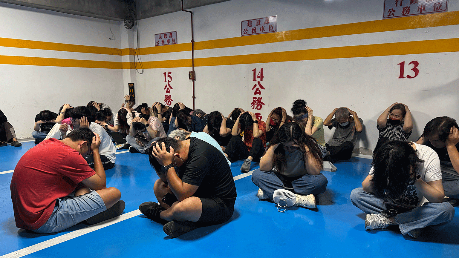 Personas en Kinmen con las manos sobre la cabeza sentadas en el suelo, como parte de uno de los simulacros.