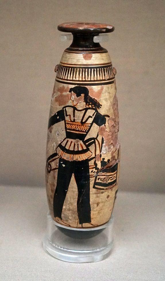 Un vaso de colores dorado y negro en el que está dibujada una mujer con unos pantalones negros