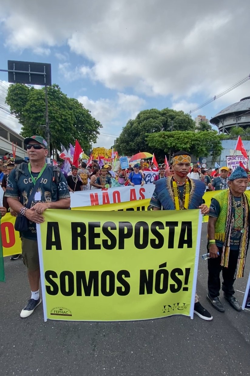 Manifestantes indígenas segurando um cartaz onde se lê 
