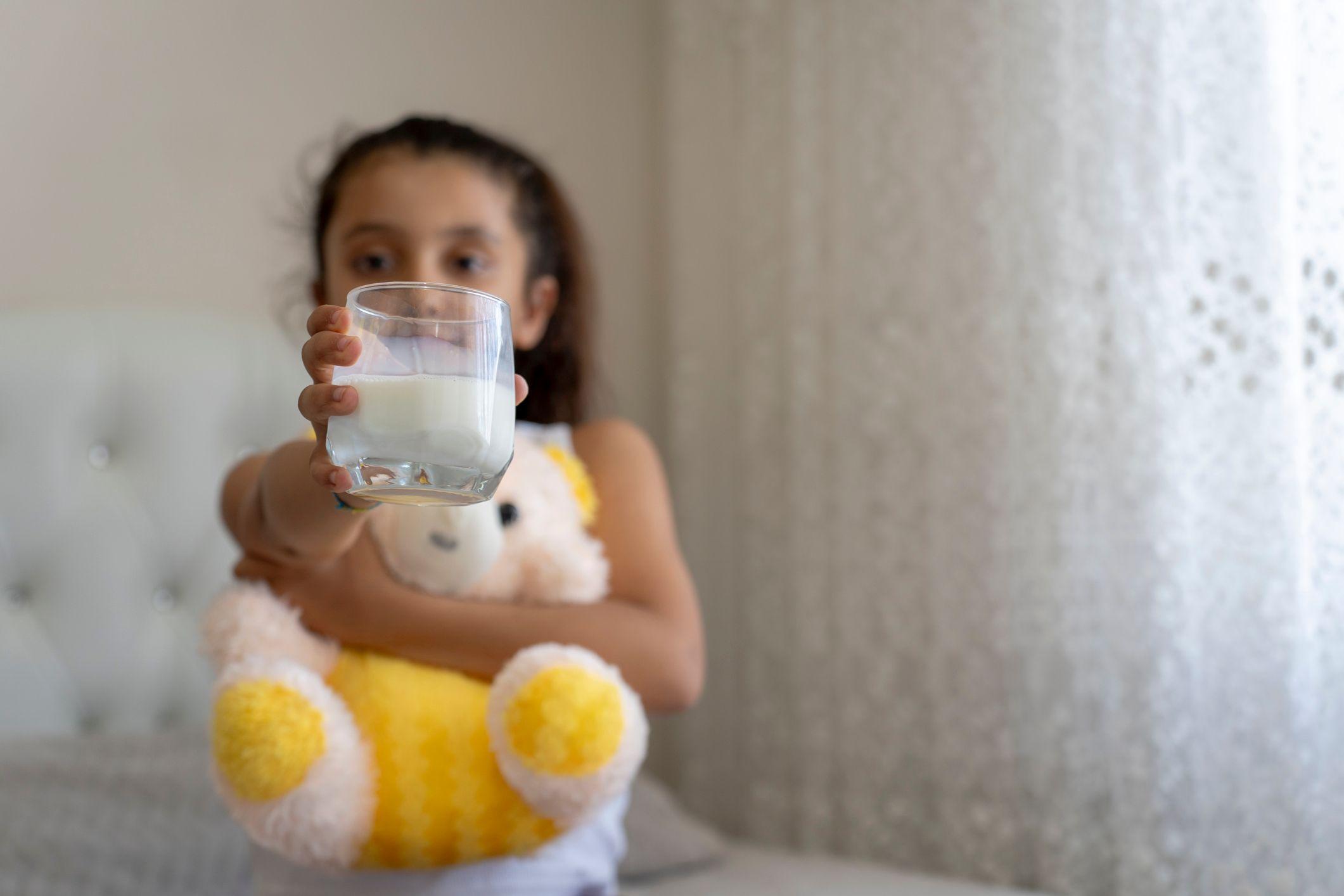 Una niña con un vaso de leche en la mano