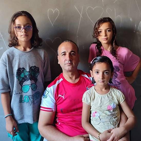  Alathamna con tres de sus hijos, todos miran fijamente a la cámara.
