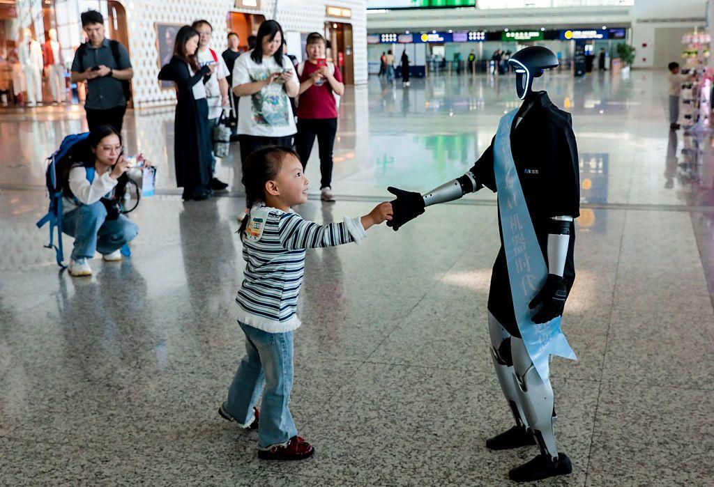 Uma criança aperta a mão de um robô humanoide Unitree G1 durante uma ação de marketing no Aeroporto Internacional Tianhe de Wuhan em 15 de abril de 2025 em Wuhan, província de Hubei, na China