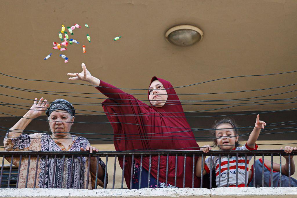 سيدة تلقي الحلوى خلال مرور موكب الاحتفال بالمولد النبوي في القاهرة 27 سبتمبر/أيلول 2023