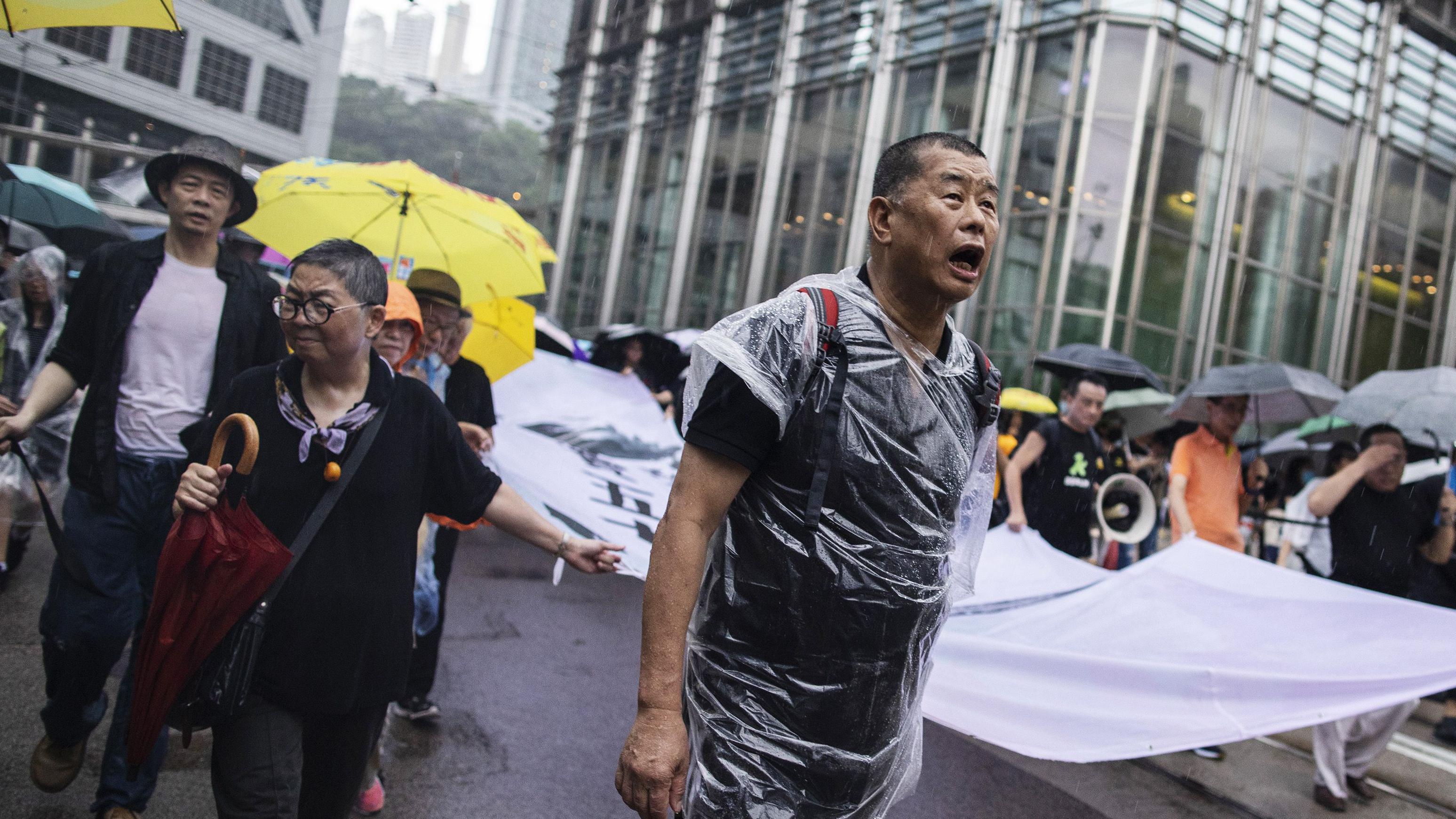 香港「反送中」示威期間黎智英在其中一場遊行裏冒雨拉起隊頭大型橫幅（18/8/2019）