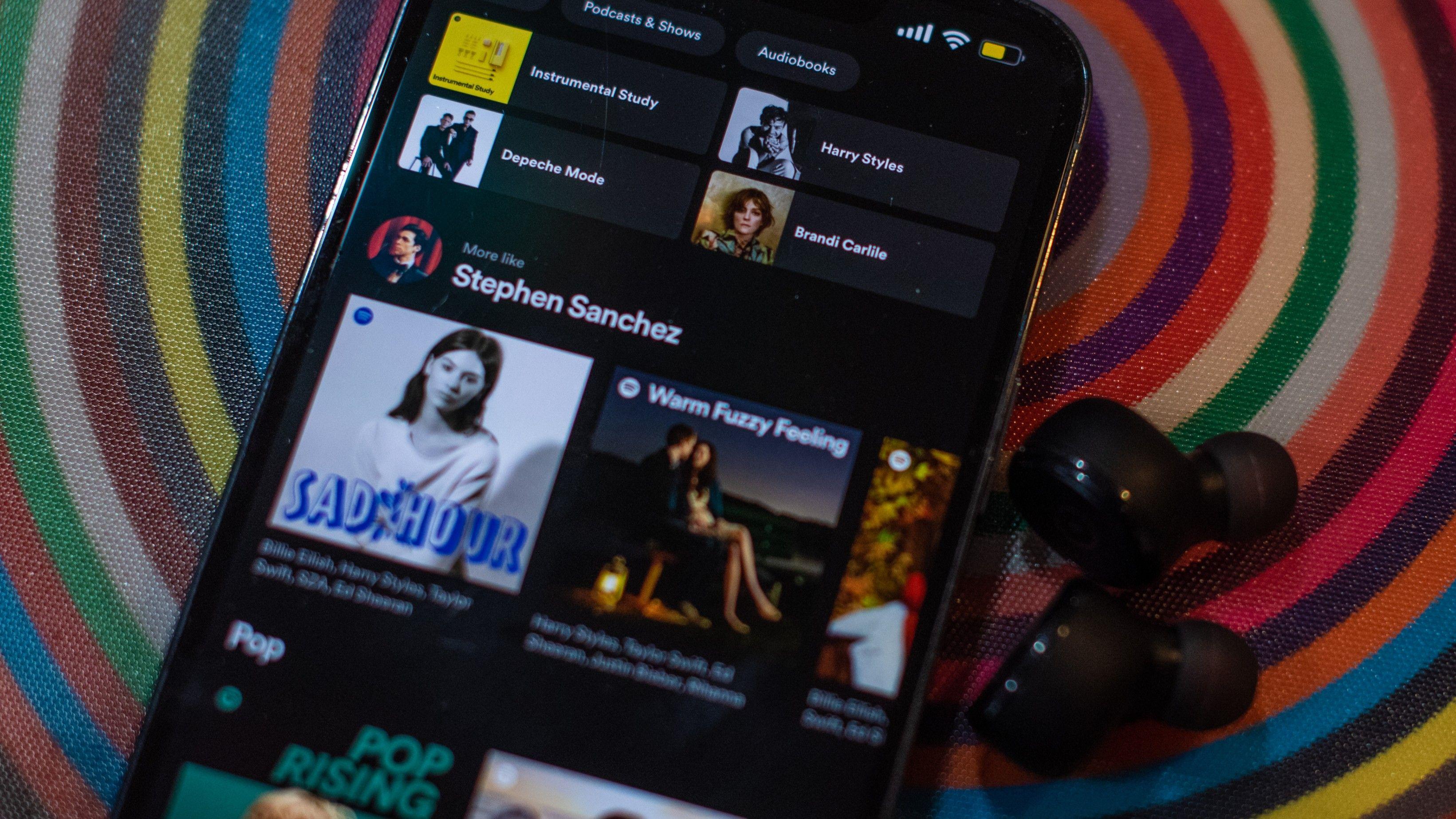 Um celular mostrando o aplicativo do Spotify com v&aacute;rios m&uacute;sicos 
