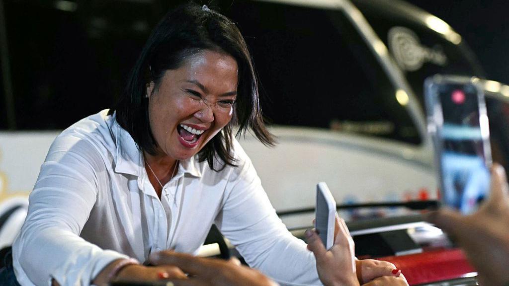 Keiko Fujimori, saluda a sus seguidores durante un mitin de campaña en Huacho, al norte de Lima, Perú, el 2 de junio de 2026. Lleva una camisa blanca y sonríe mientras agarra las manos de varias personas que están allí para saludarla.