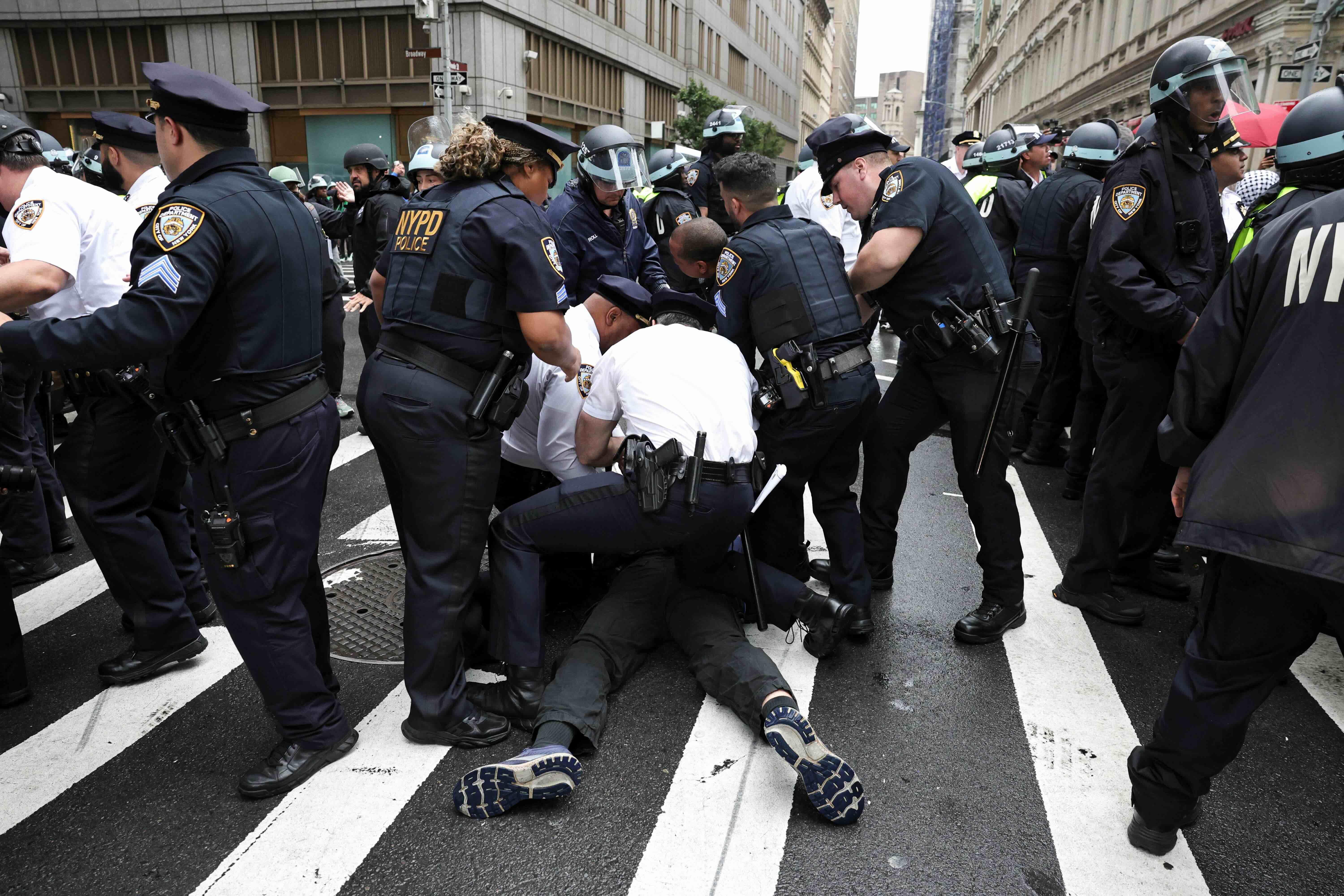Un grupo de policía está inmovilizando a un manifestante en el piso en las calles de Nueva York.