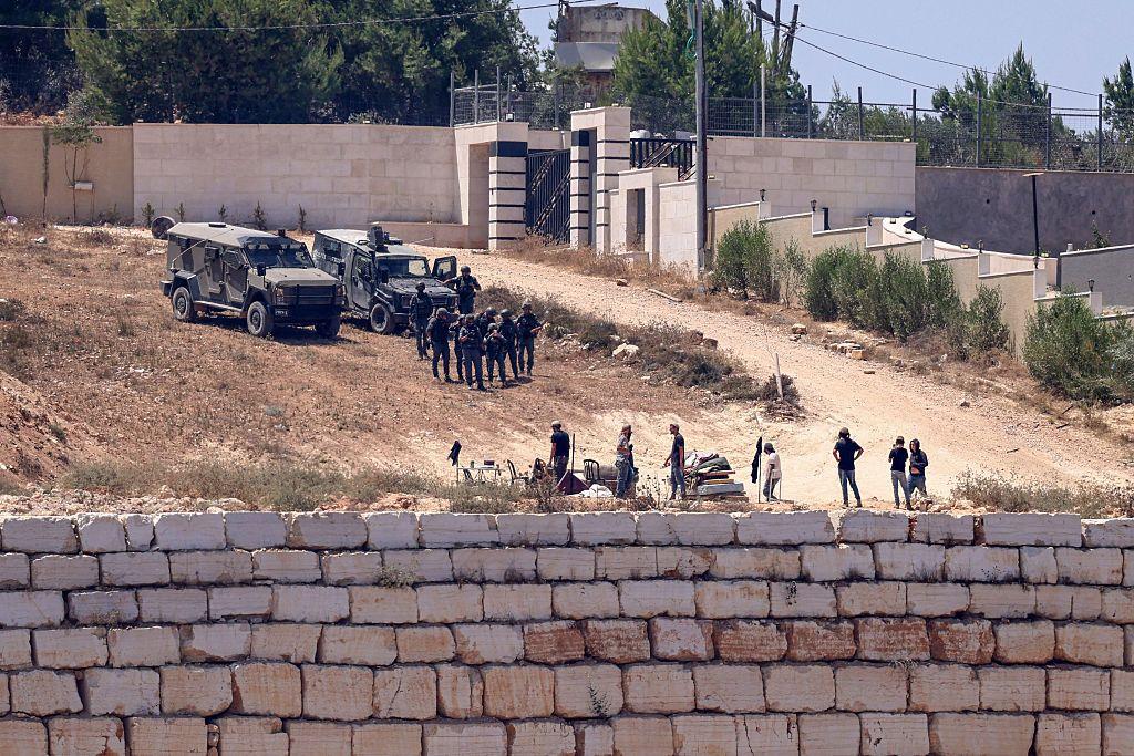 Soldados israelíes montan guardia  frente a las casas palestinas en la aldea de Qusra, al sur de Nablus. Frente a ellos hay un grupo de colonos.