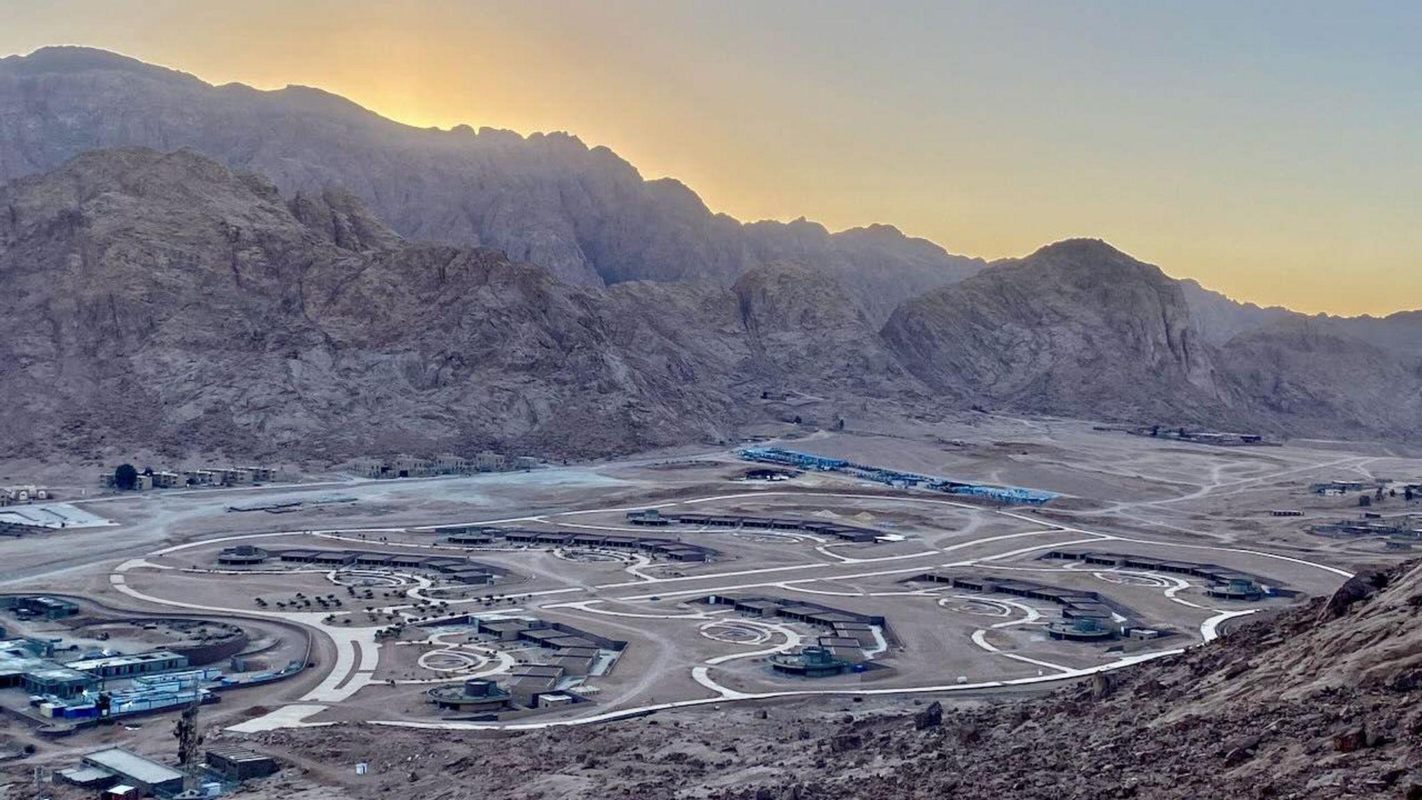 拉哈平原仍在建設中的開發案之一。太陽在山脈背後，而開發地塊位於前景中，道路連接著不同的建築。