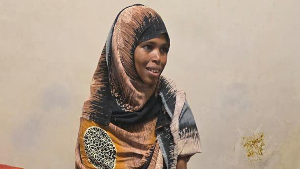 Primer plano de Bedriya sonriendo. Lleva un pañuelo estampado con motivos verdes y amarillos.