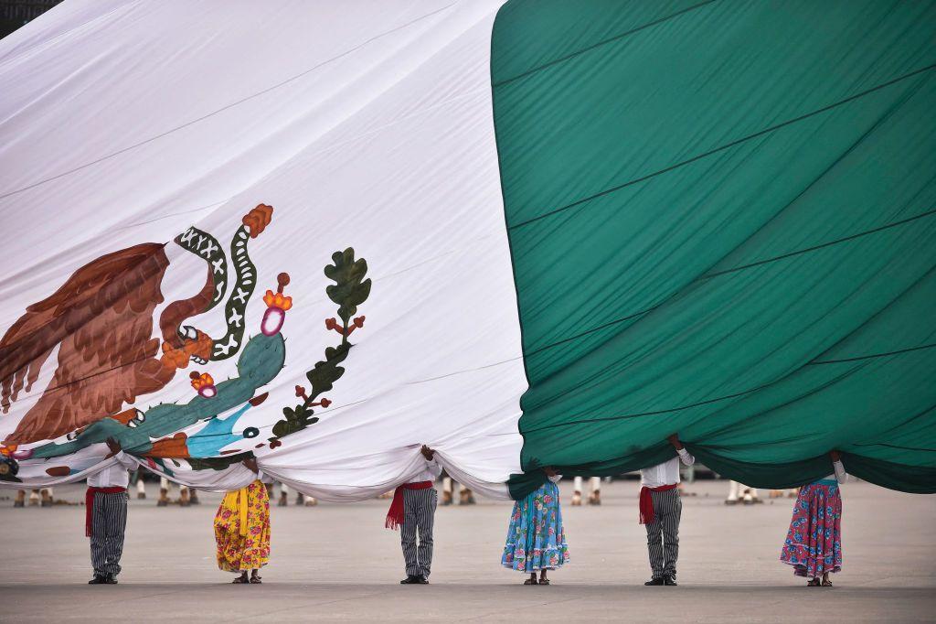Bandera de México sobre seis personas en una plaza