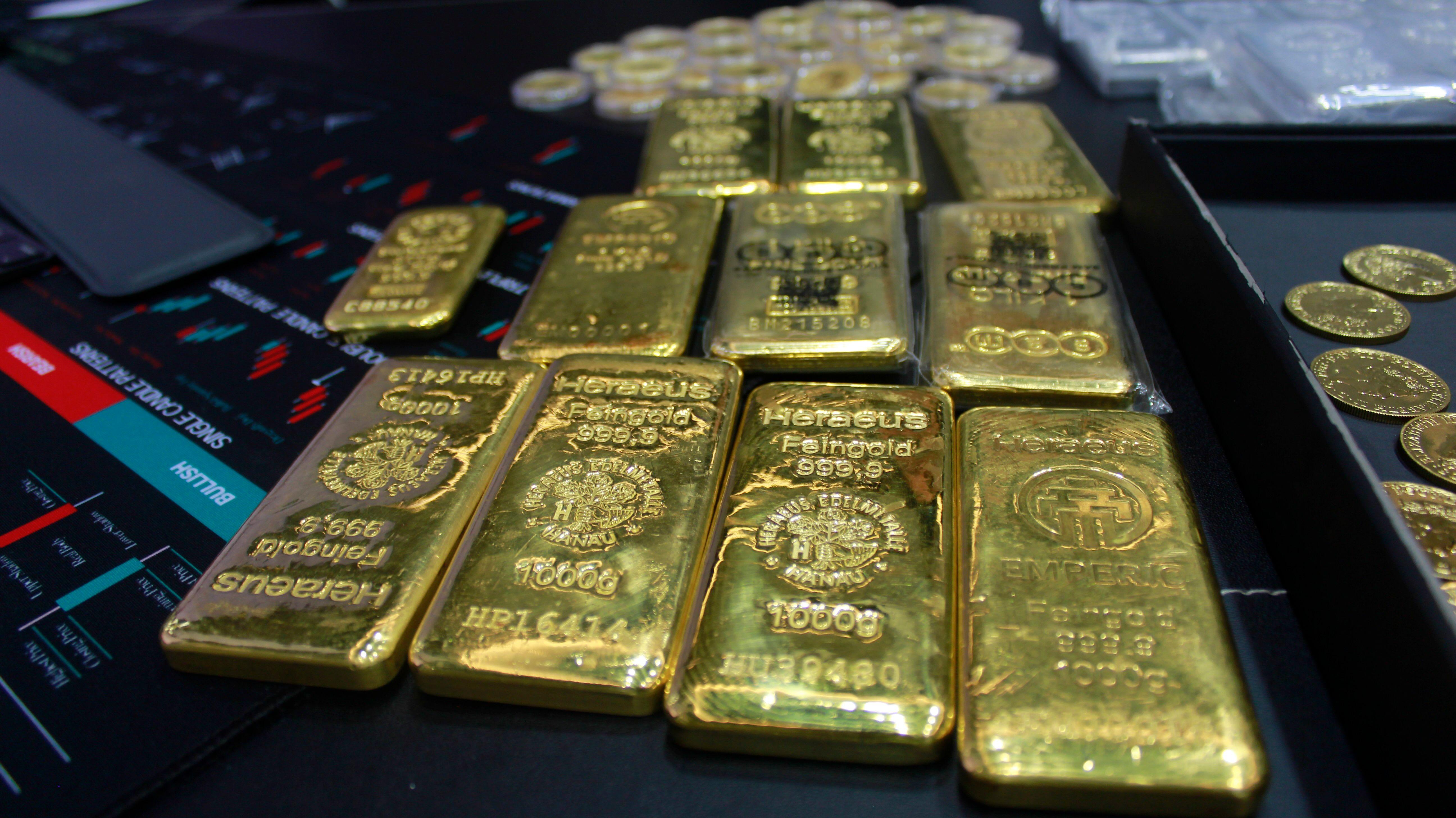圖片顯示有多條1000g的黃金金條及一些金幣。