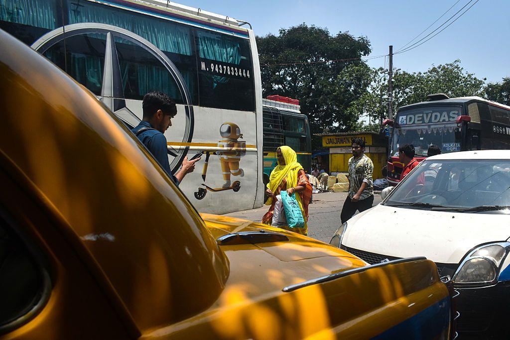 Una mujer camina por una calurosa calle en el verano de Calcuta, India. El caliente sol brilla con intensidad.