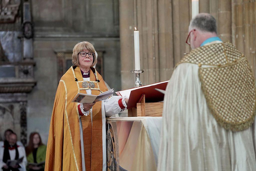 Sarah Mullaly juramenta con una mano en una gran biblia, y el decano de Canterbury al frente suyo.