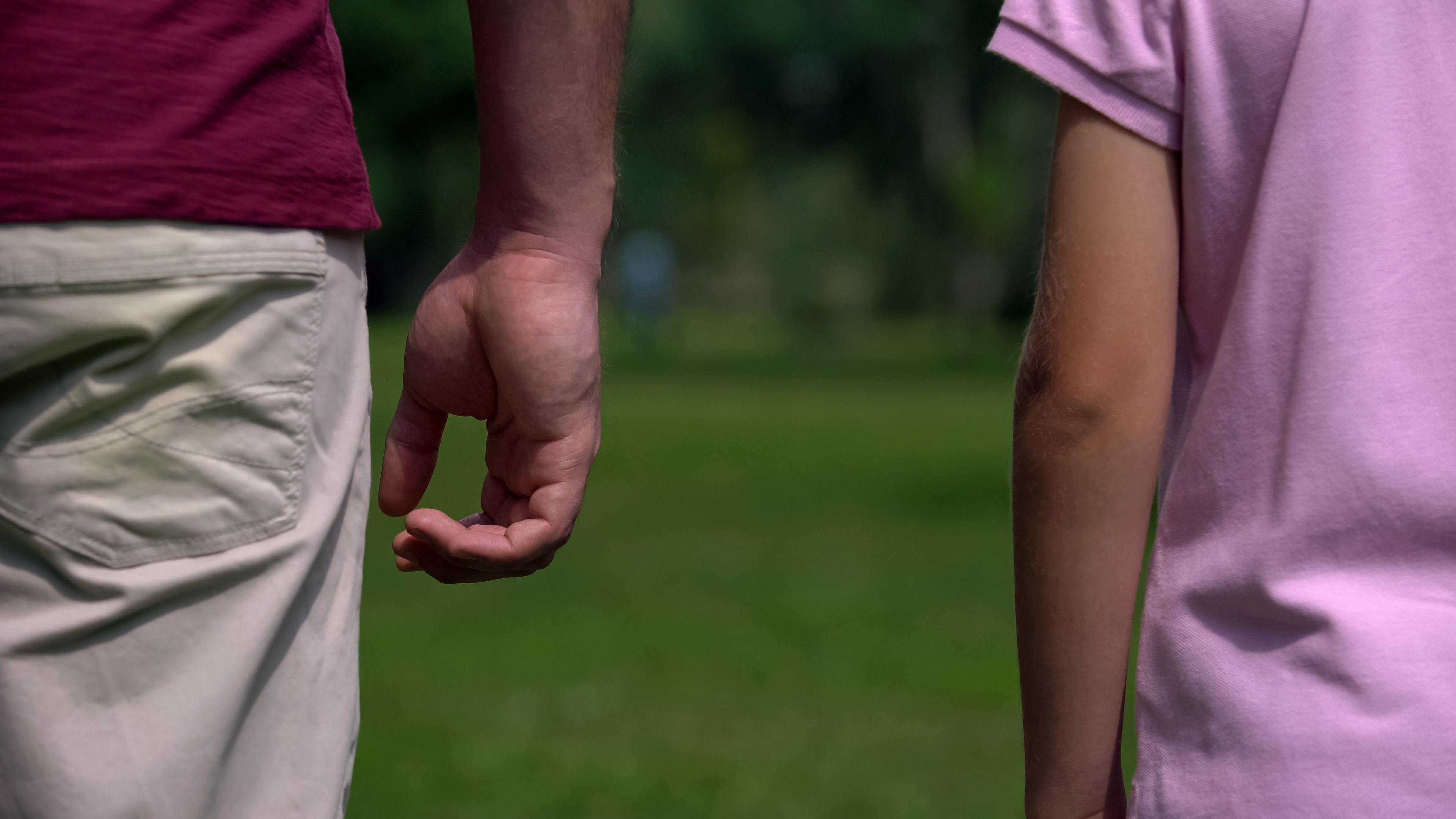 La mano de un padre y el brazo de un hijo distanciados