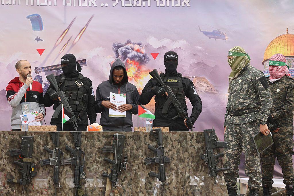 Los rehenes israelíes Avera Mengistu (cuarto por la derecha) y Tal Shoham (izq.) están flanqueados por combatientes palestinos de Hamas mientras están en un escenario durante su liberación en Rafah, en el sur de la Franja de Gaza, el 22 de febrero de 2025.
