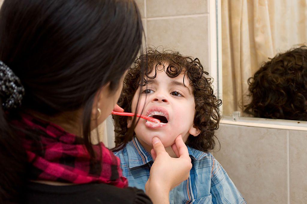 Uma mulher escovando o dente de uma criança