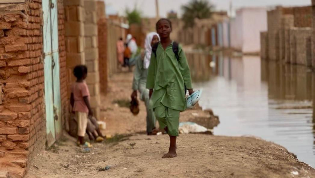 طفل يسير وسط مياه الفيضان