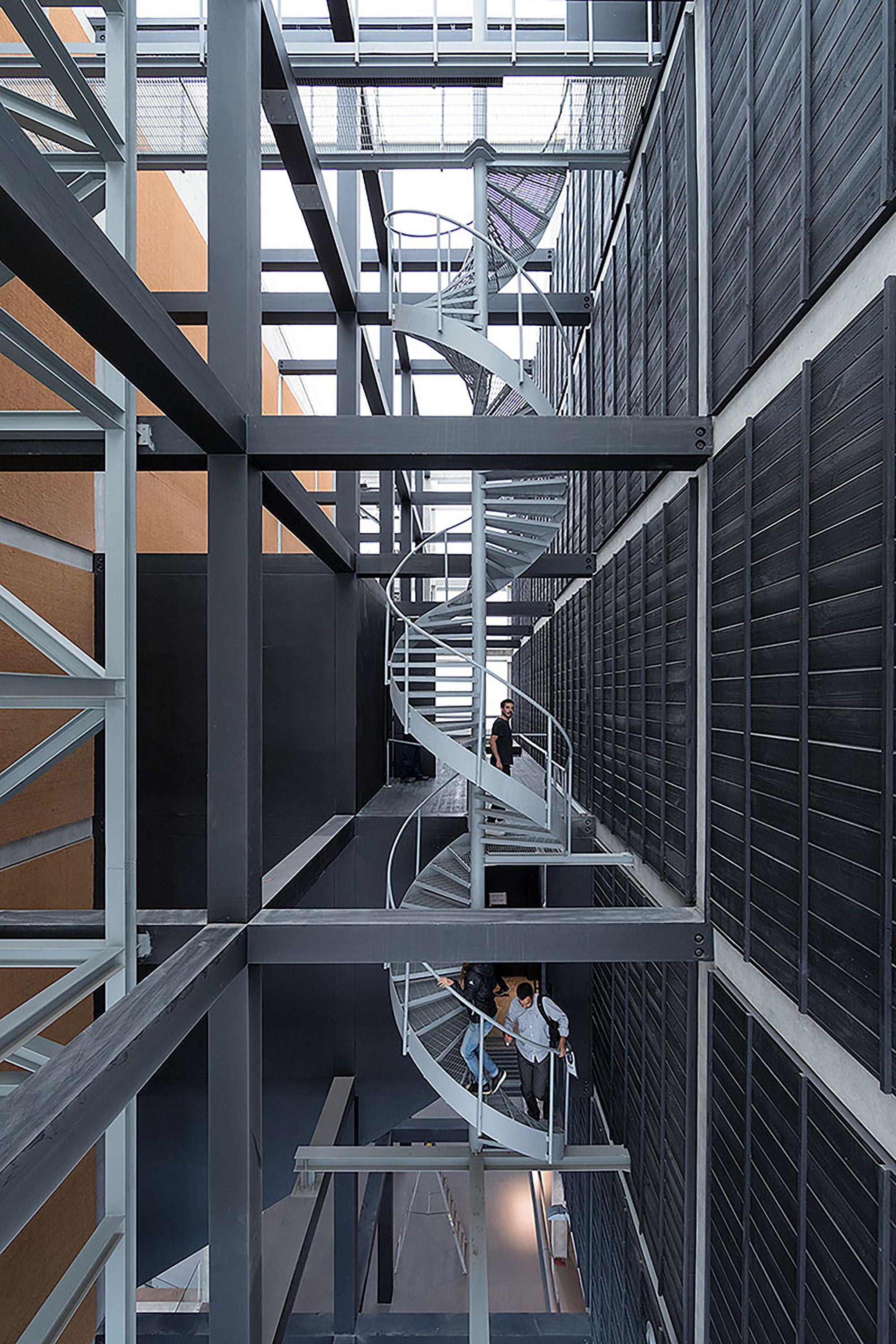 Escalera caracol metálica integrada en una estructura industrial con marcos y pasarelas de acero.