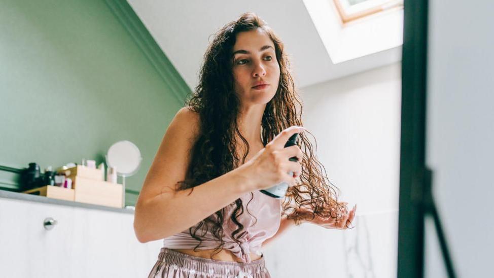 Mujer aplicándose un producto en las puntas del cabello