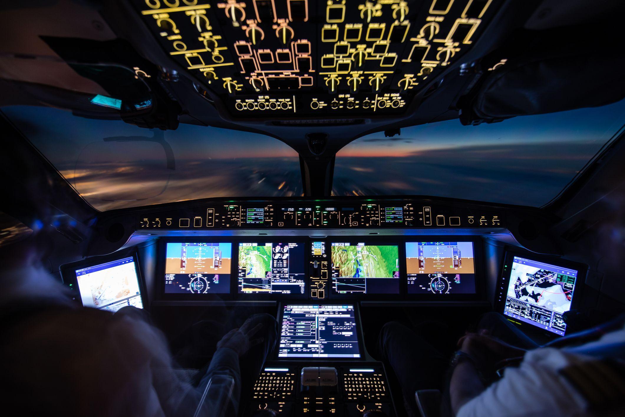 Vista de la cabina de mando de un avión y dos pilotos en ella. 