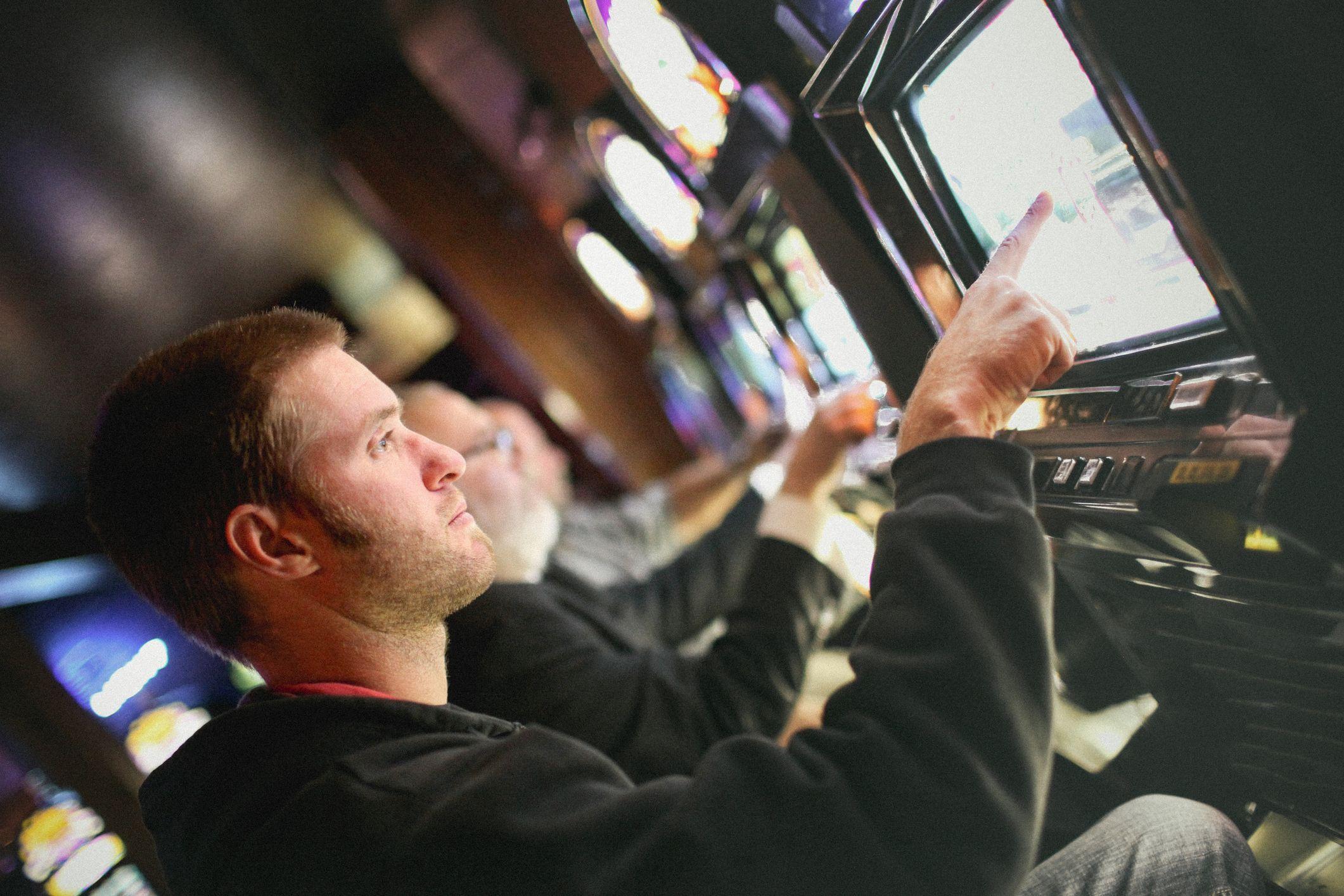 Homens sentados lado a lado em frente a máquinas de cassino