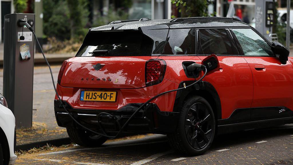 Carro el&eacute;trico vermelho abastecendo em um ponto na cidade holandesa de Haia