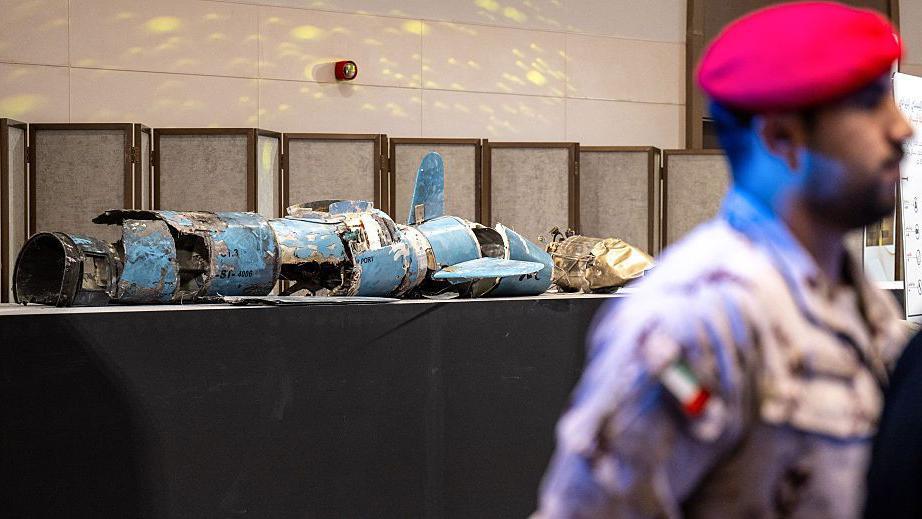 جندي إماراتي خلفه طاولة عرض عليها بقايا صواريخ منفجرة