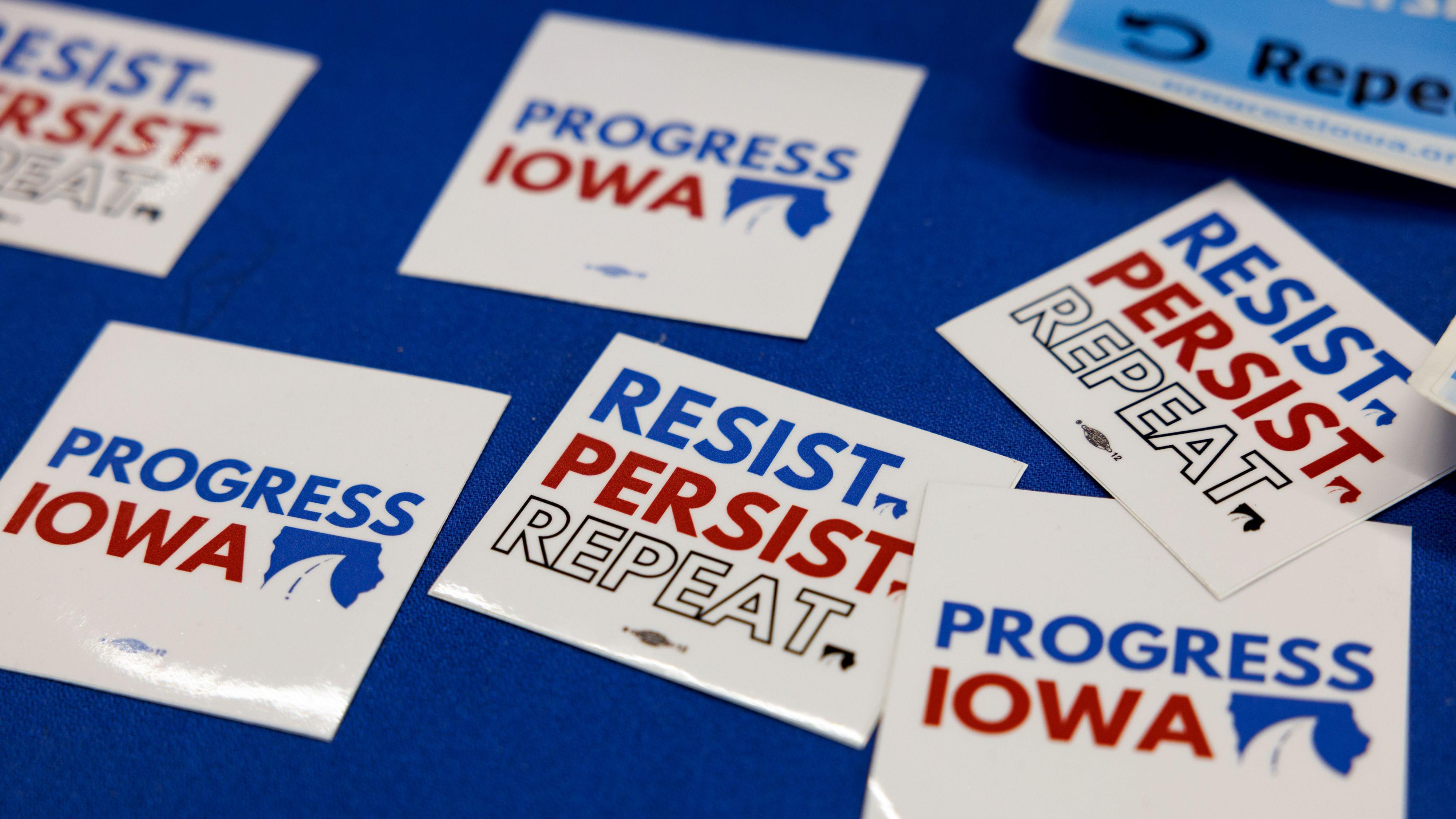 Insígnias com os dizeres: Resista. Persista. Repita. Progresso de Iowa.