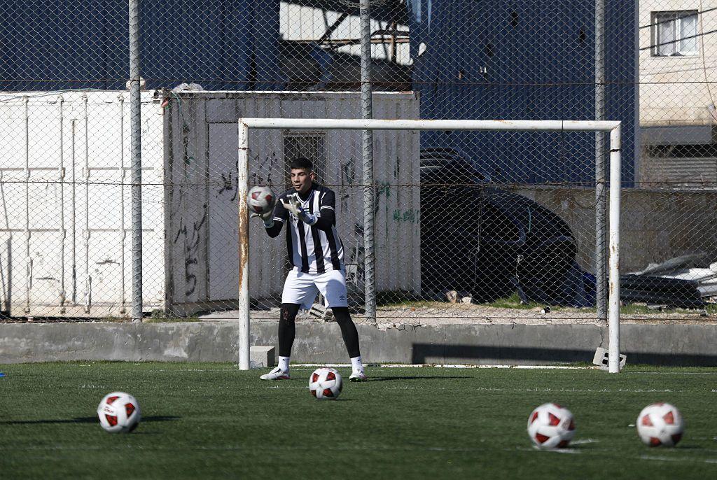 Un joven arquero para un balón durante la práctica en el campo a punto de ser demolido