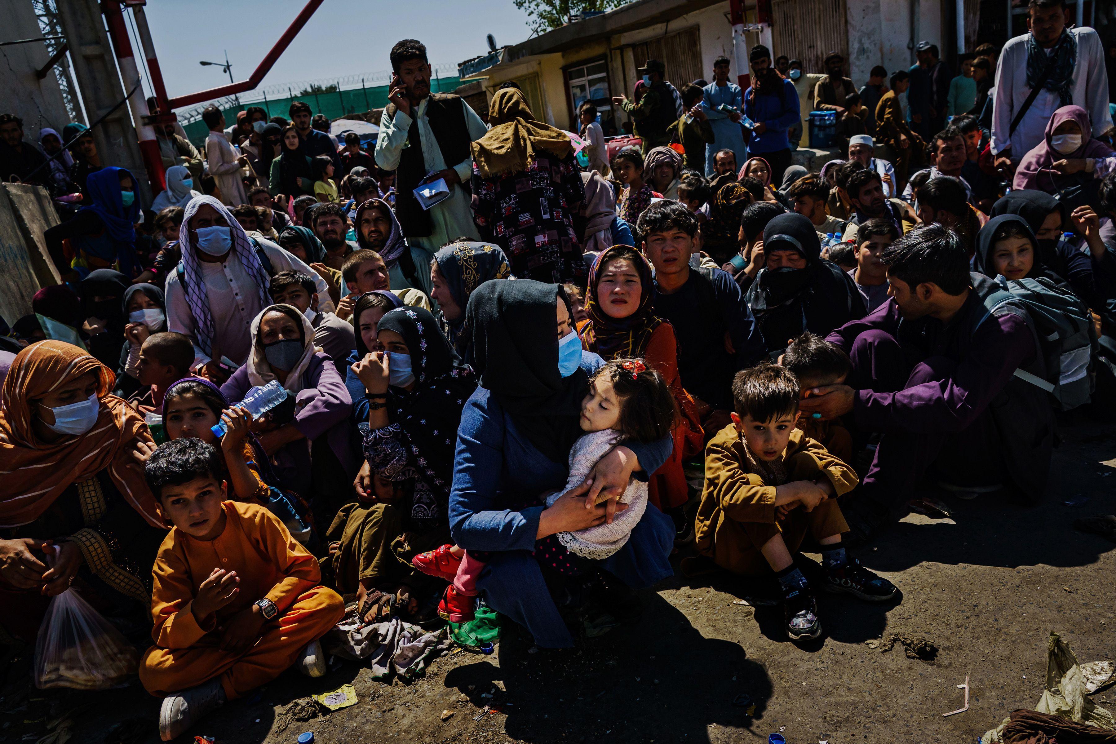 Women and children crouch in the sweltering heat at a Taliban-controlled checkpoint near Abbey Gate, an entrance to the Kabul airport on Aug. 25, 2021. They wait to make their way towards the British military-controlled entrance of the airport