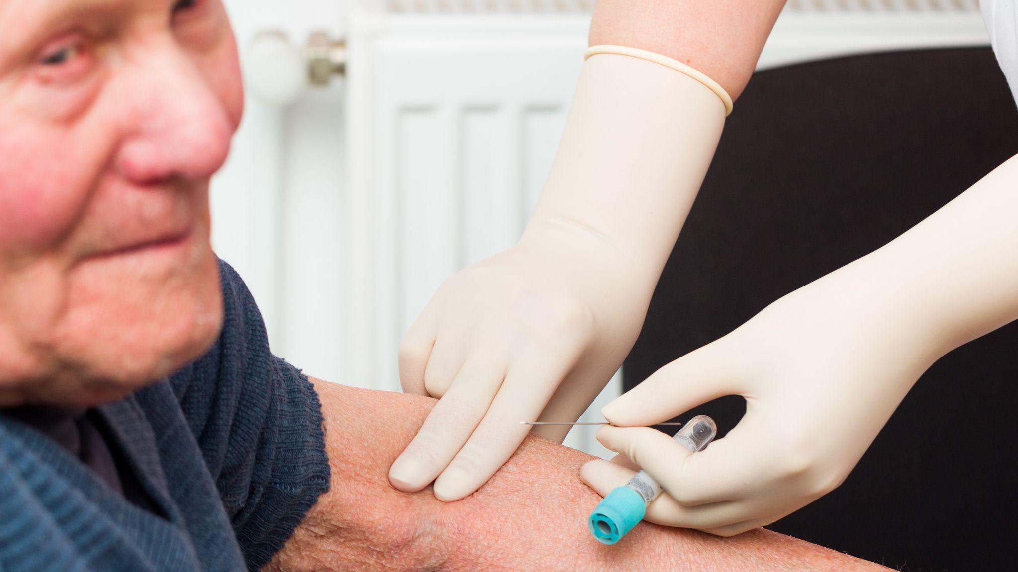 una persona tomando una muestra de sangre a un adulto mayor 