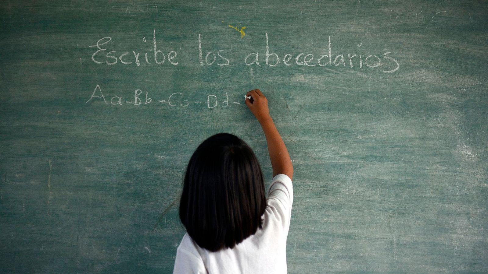 Niño escribe en una pizarra palabras en español