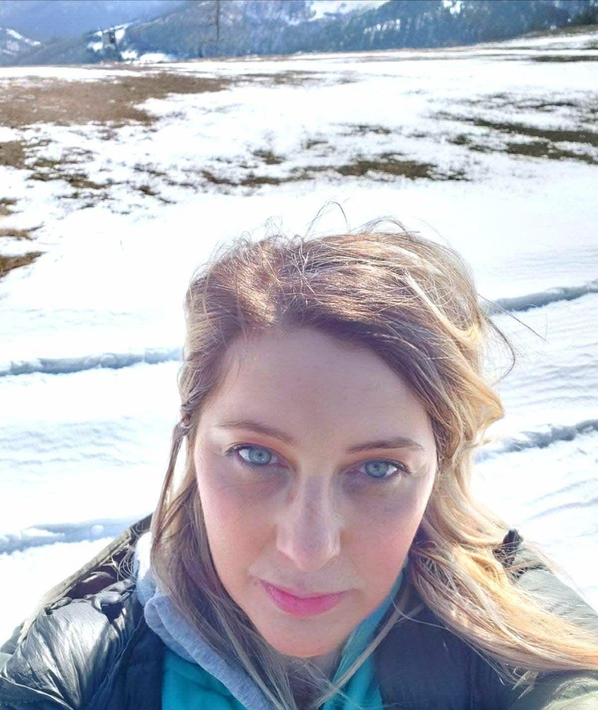 Nikolina Crnogorac fotografiše samu sebe, iza nje se vidi sneg, nosi crnu jaknu ima smeđu kosu 