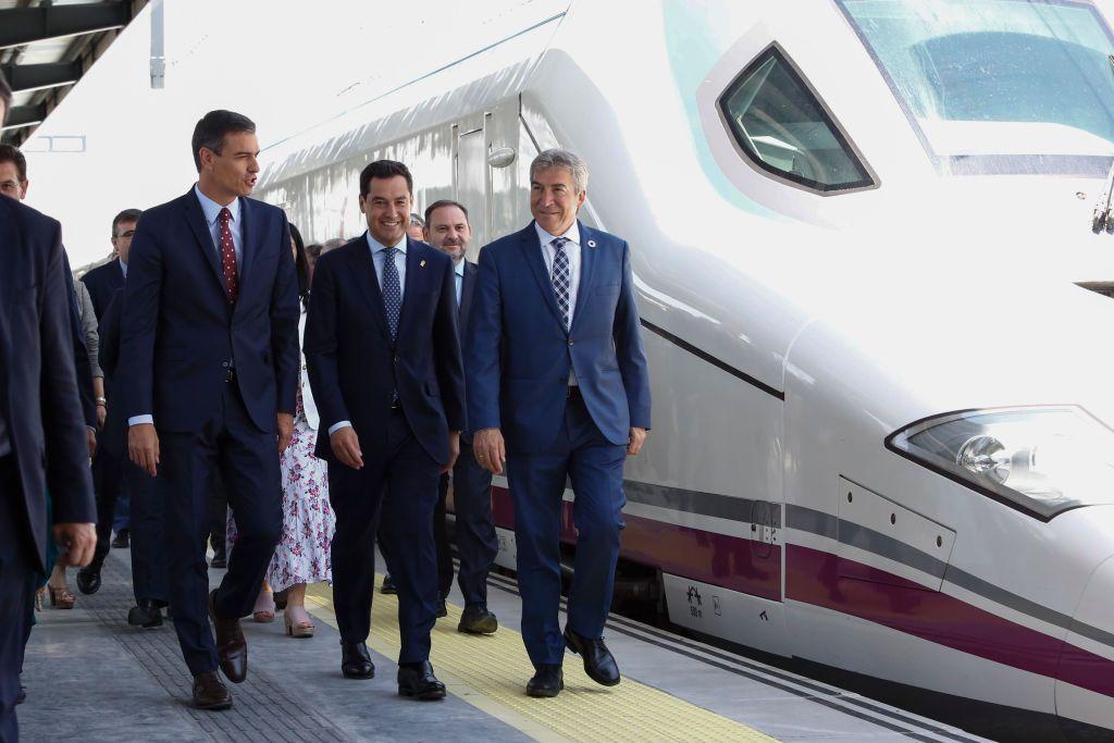 El presidente del gobierno español, Pedro Sánchez, (i) camina sonriente junto a un tren de alta velocidad estacionado con el presidente regional de Andalucía, Juanma Moreno (c) y otras autoridades en la inauguración del servicio AVE entre Madrid y Granada.