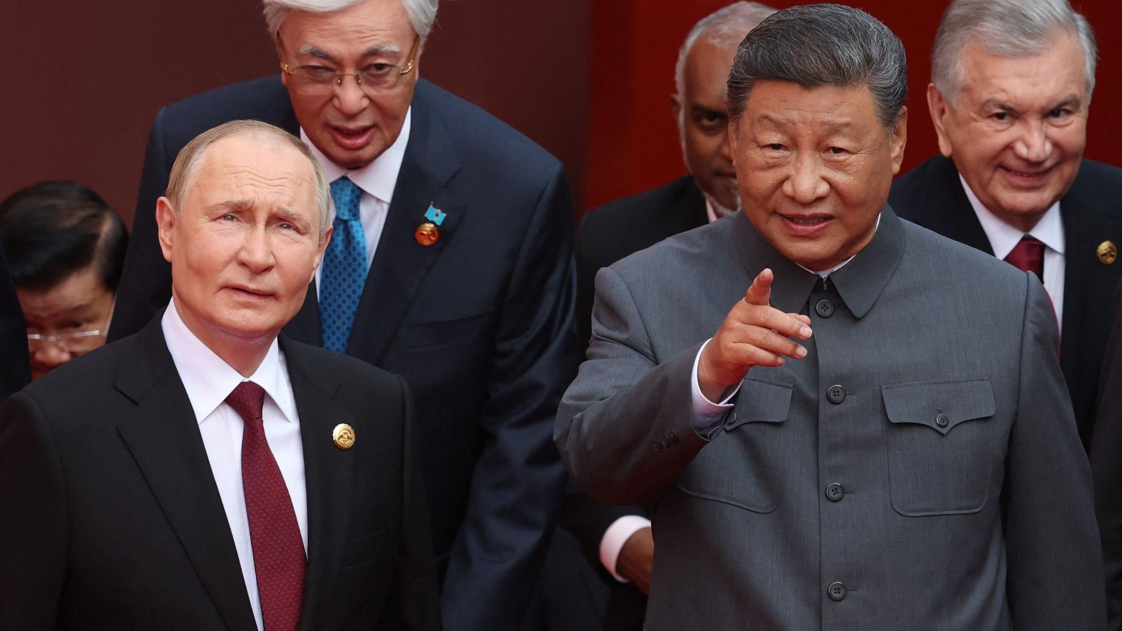 شي يقف بجانب بوتين ويشير إلى الكاميرا