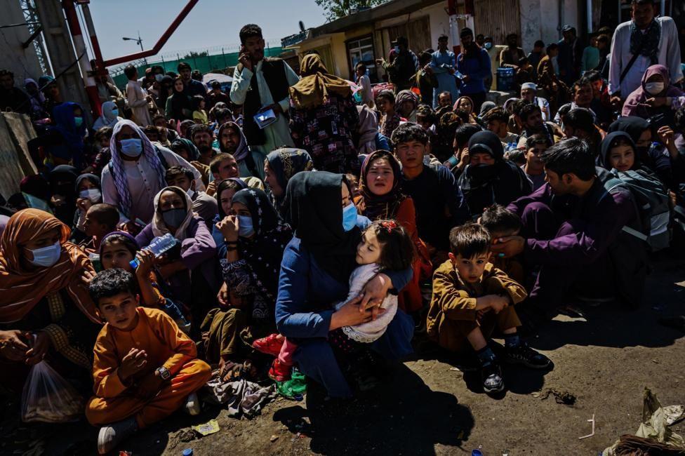 Mujeres con niños en brazos, numerosos niños y adultos congregados en el aeropuerto en Kabul en 2021 con la esperanza de ser evacuados junto con tropas extranjeras