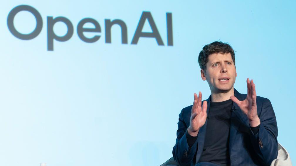 سام ألتمان متحدثاً في جلسة حوارية وقد كُتب وراءه اسم شركة أوبن إيه آي Open AI