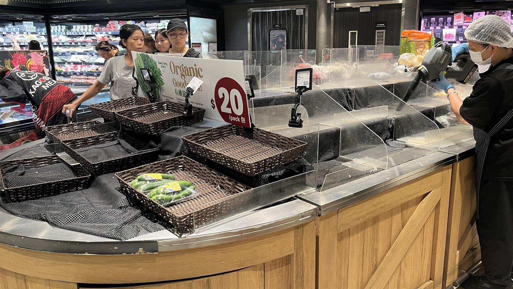 香港將軍澳某超市內一位女店員（右）拿著吸塵機清潔已被買空的蔬菜貨架（BBC中文圖片22/9/2025）