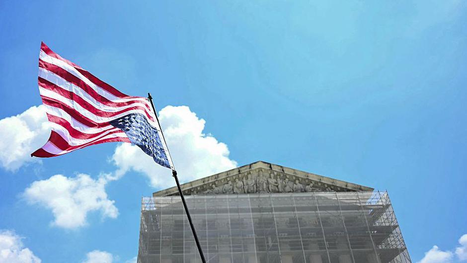 Una bandera de Estados Unidos ondea del revés frente a la fachada de la Corte Suprema, cubierta por un andamio.