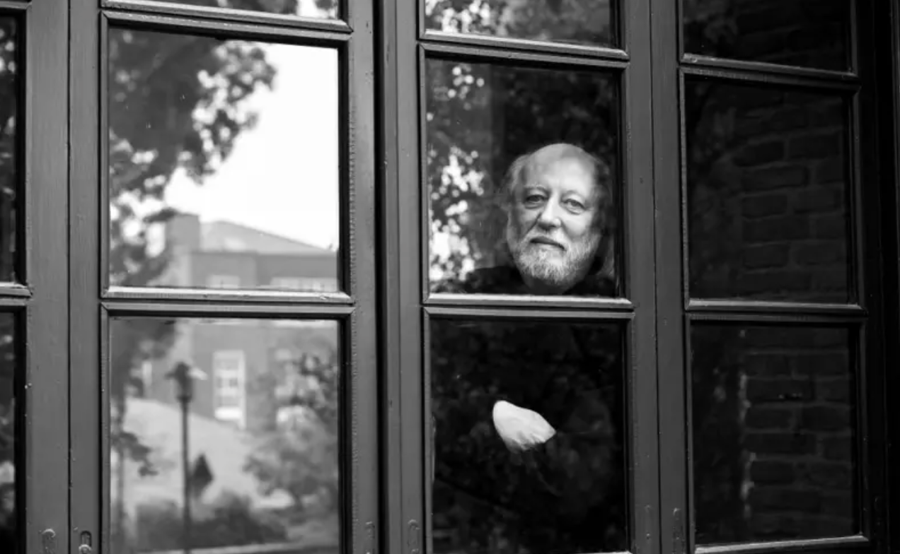 Imagem do vencedor do nobel da literatura, Krasznahorkai, atrás de uma janela, em branco e preto