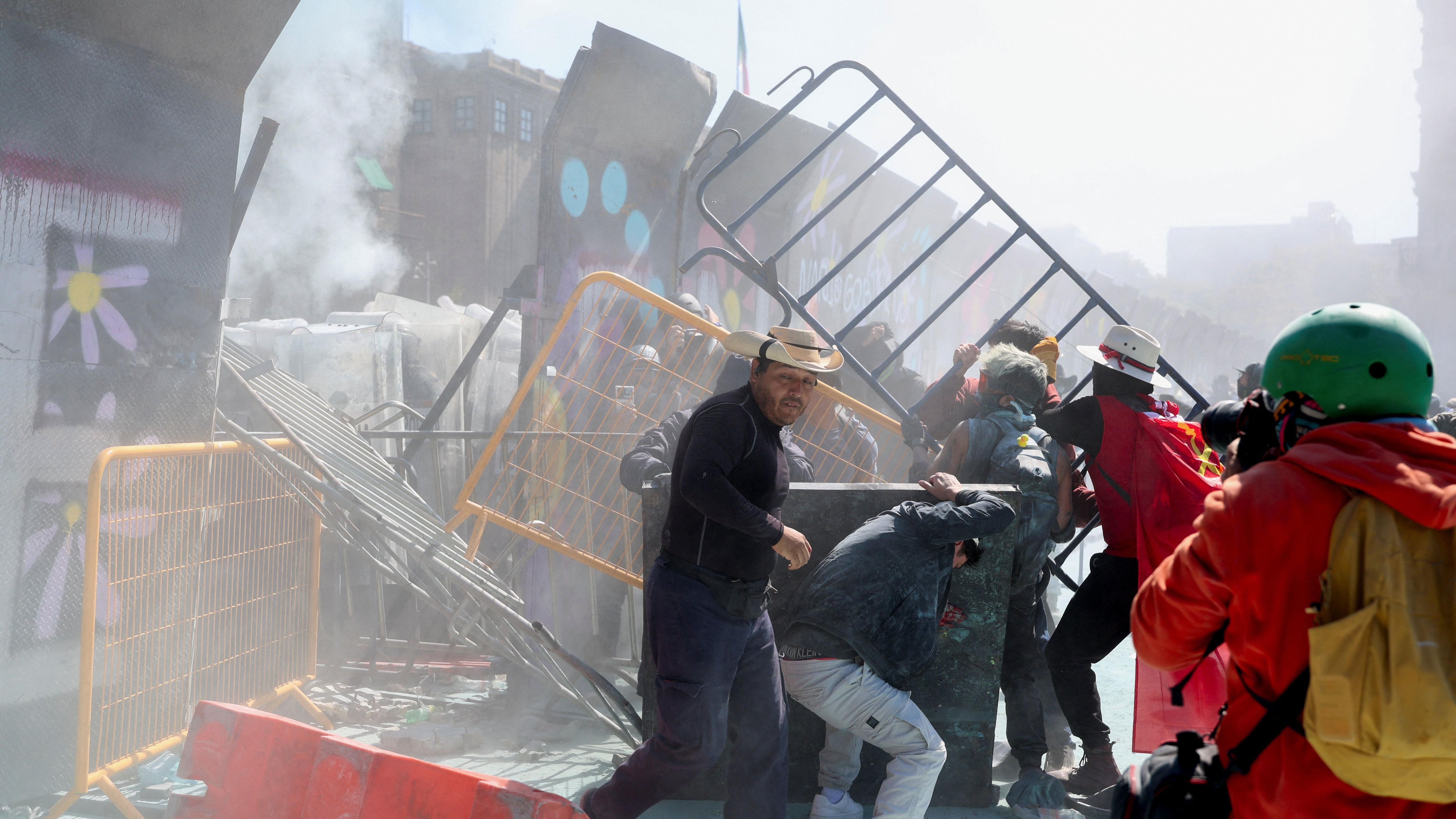 Manifestantes derriban parte de una valla que protegía el Palacio Nacional durante una protesta contra la inseguridad y la corrupción en el país, en la Plaza del Zócalo.