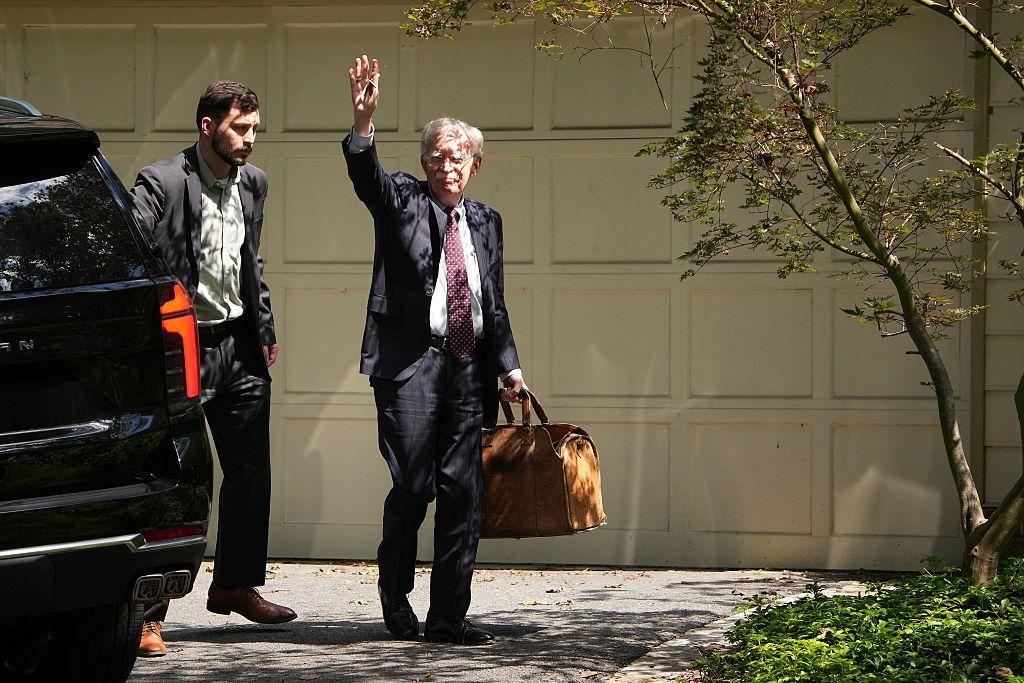 جون بولتون يلوح بيده لدى وصوله إلى منزله بعد إجراء التفتيش