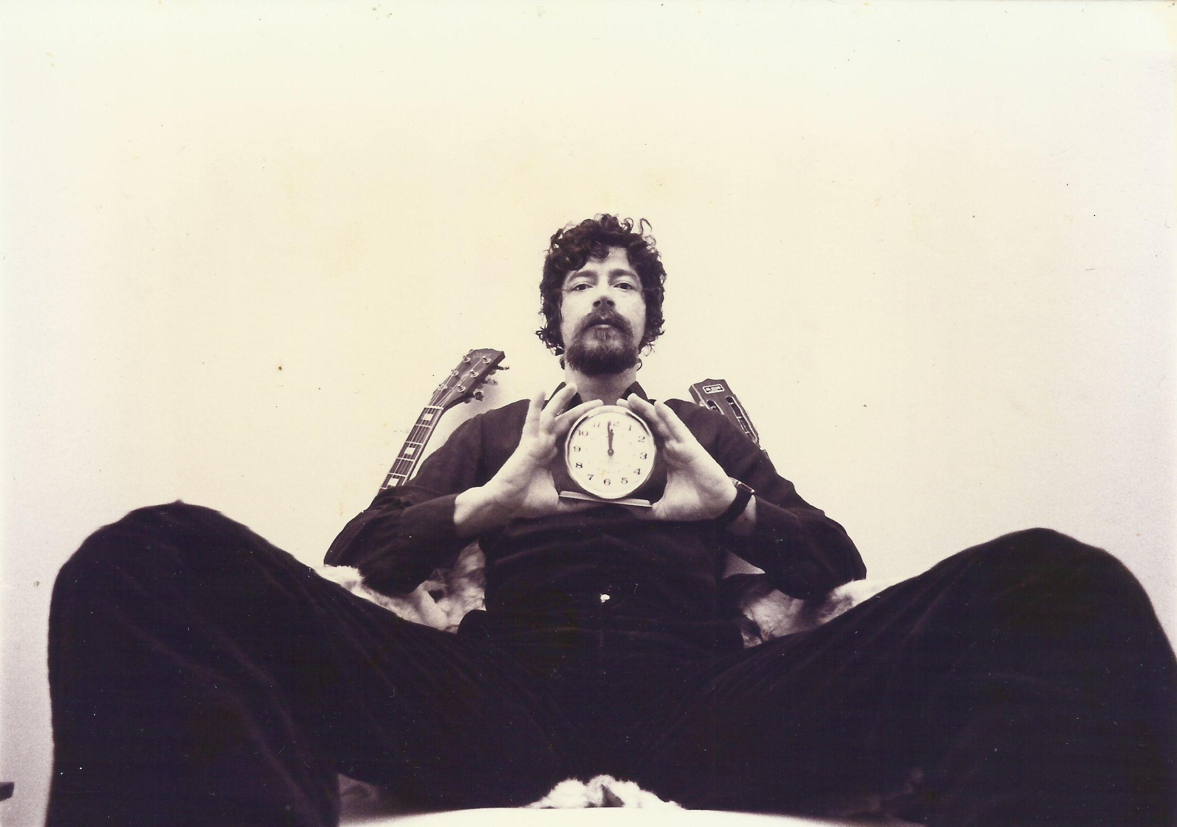 Raul Seixas sentado mostrando relógio com as mãos