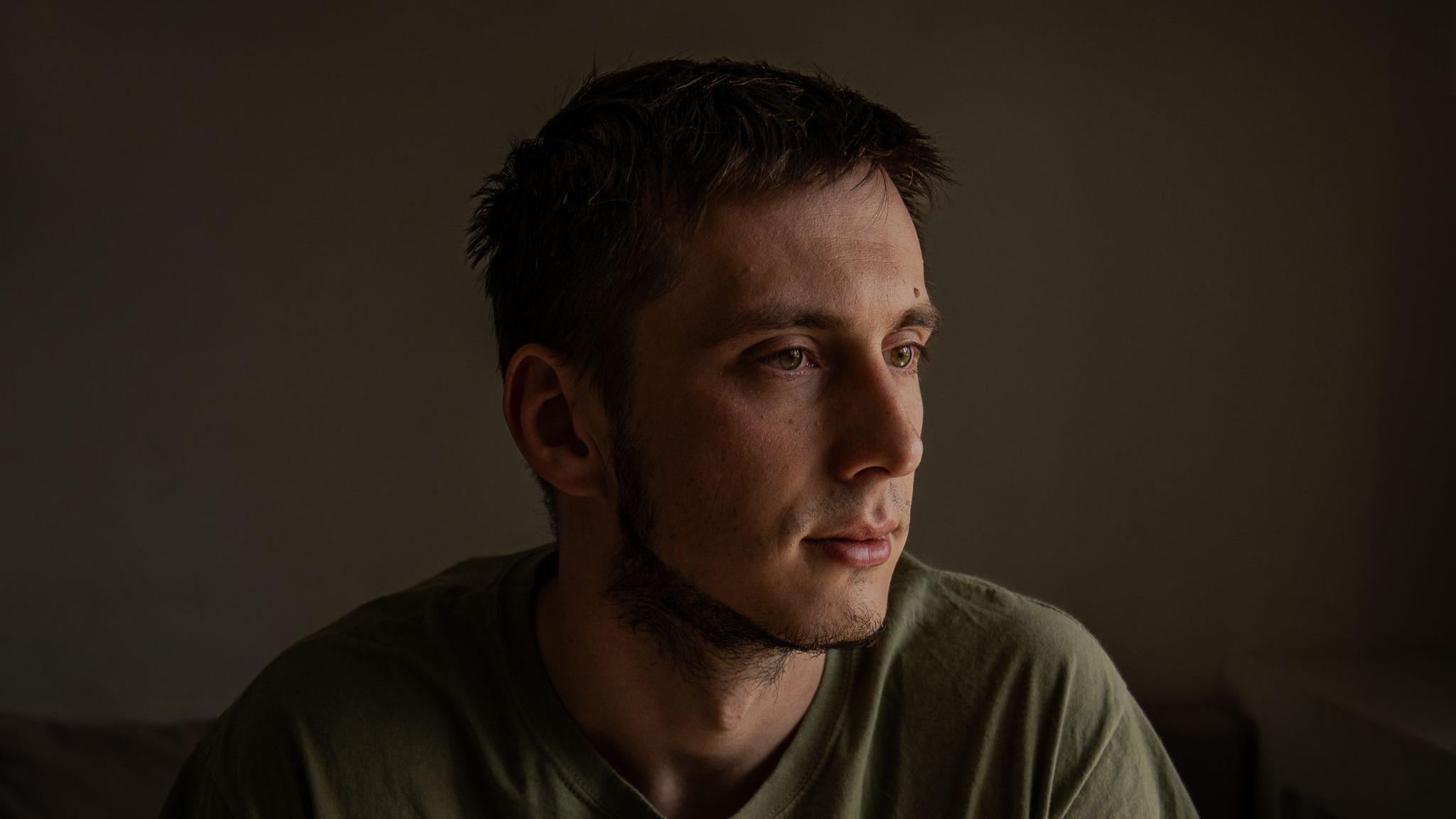 Pavlo, de cabello oscuro y vestido con una camiseta verde, aparta la mirada de la cámara.