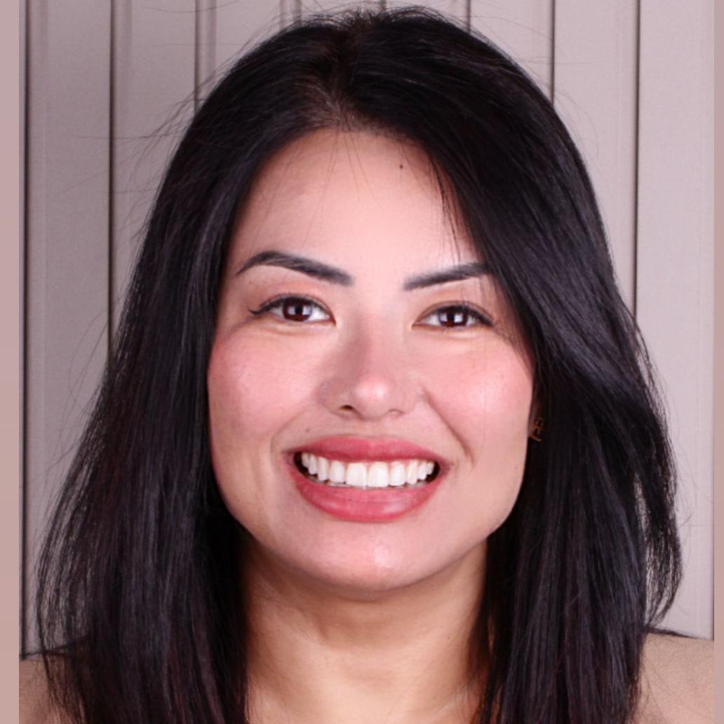 Viviana Makiyama sorrindo para foto, em frente a parede