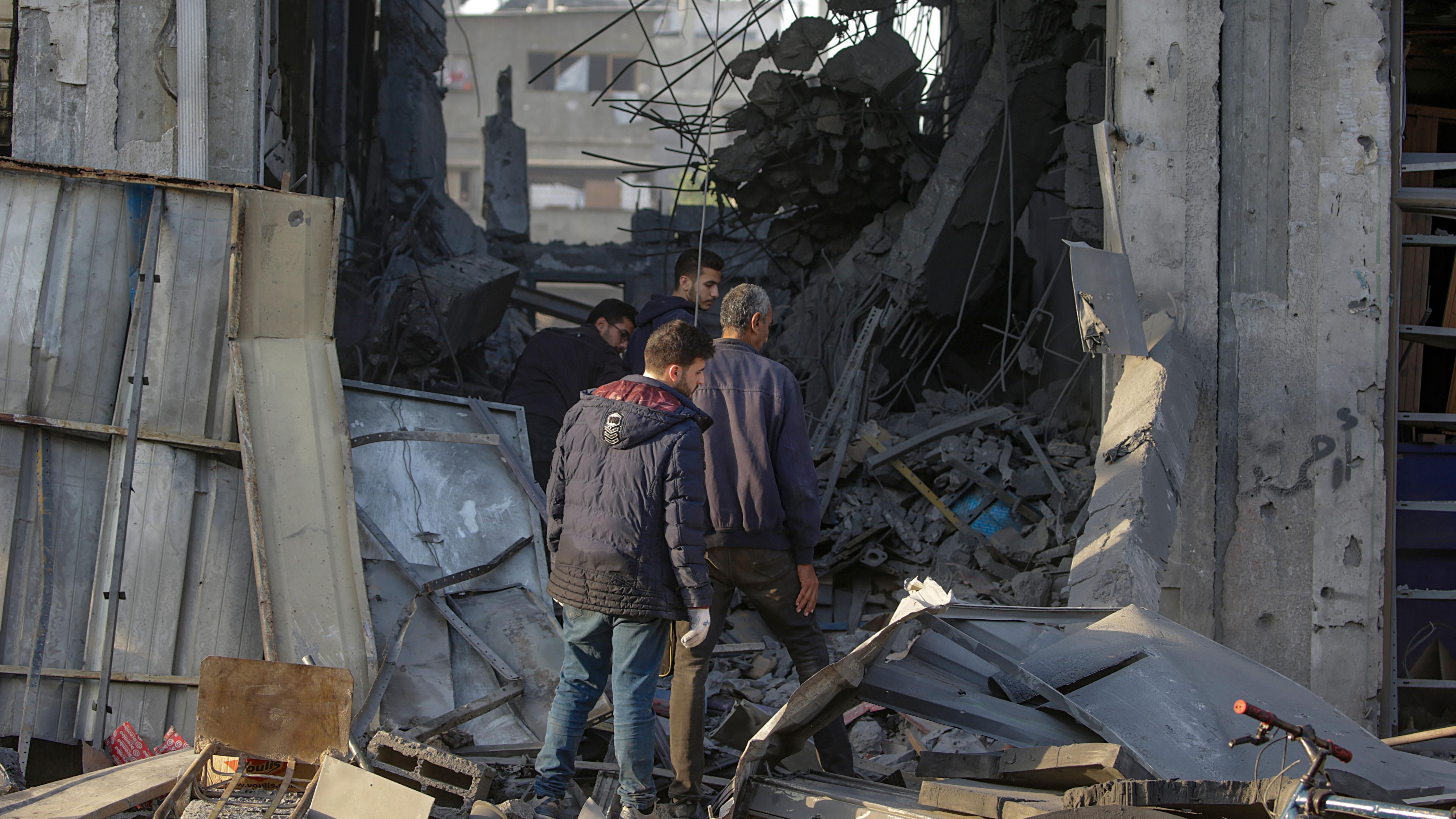 Unos hombres caminan entre los escombros de un edificio en Zeitoun, Gaza
