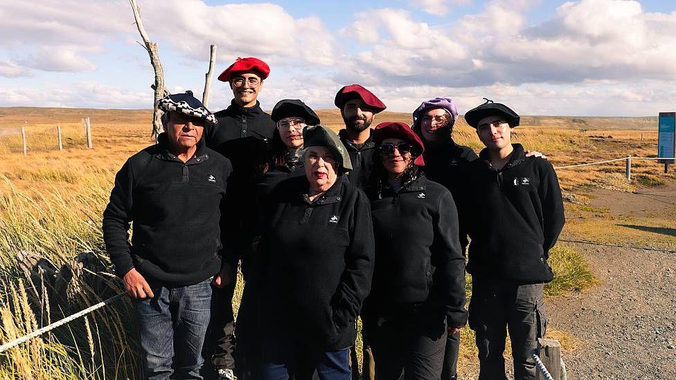Cecilia Durán Gafo junto a integrantes del equipo de la Reserva Natural Pingüino Rey. Es un grupo de 8 personas. Todas visten de negro y 3 tienen boinas rojas, 4 negras y una de ellas púrpura. 
