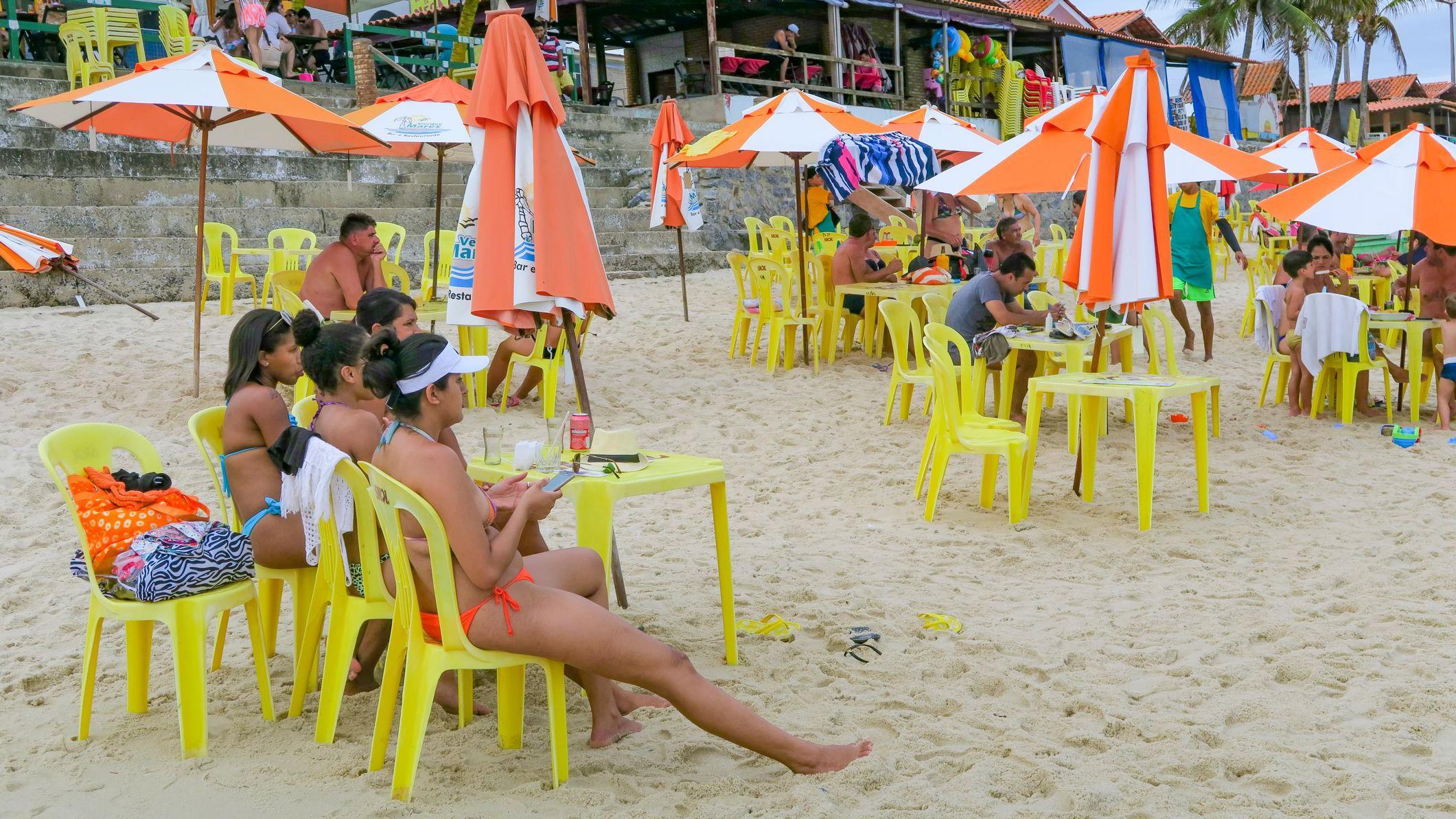 Pessoas sentadas em cadeiras monobloco na praia do Franc&ecirc;s, em Alagoas (Brasil).